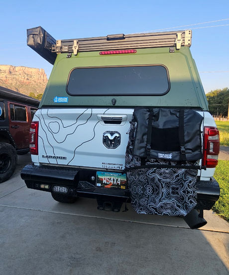Back view of a green and white camper van with roof rack and storage bags 